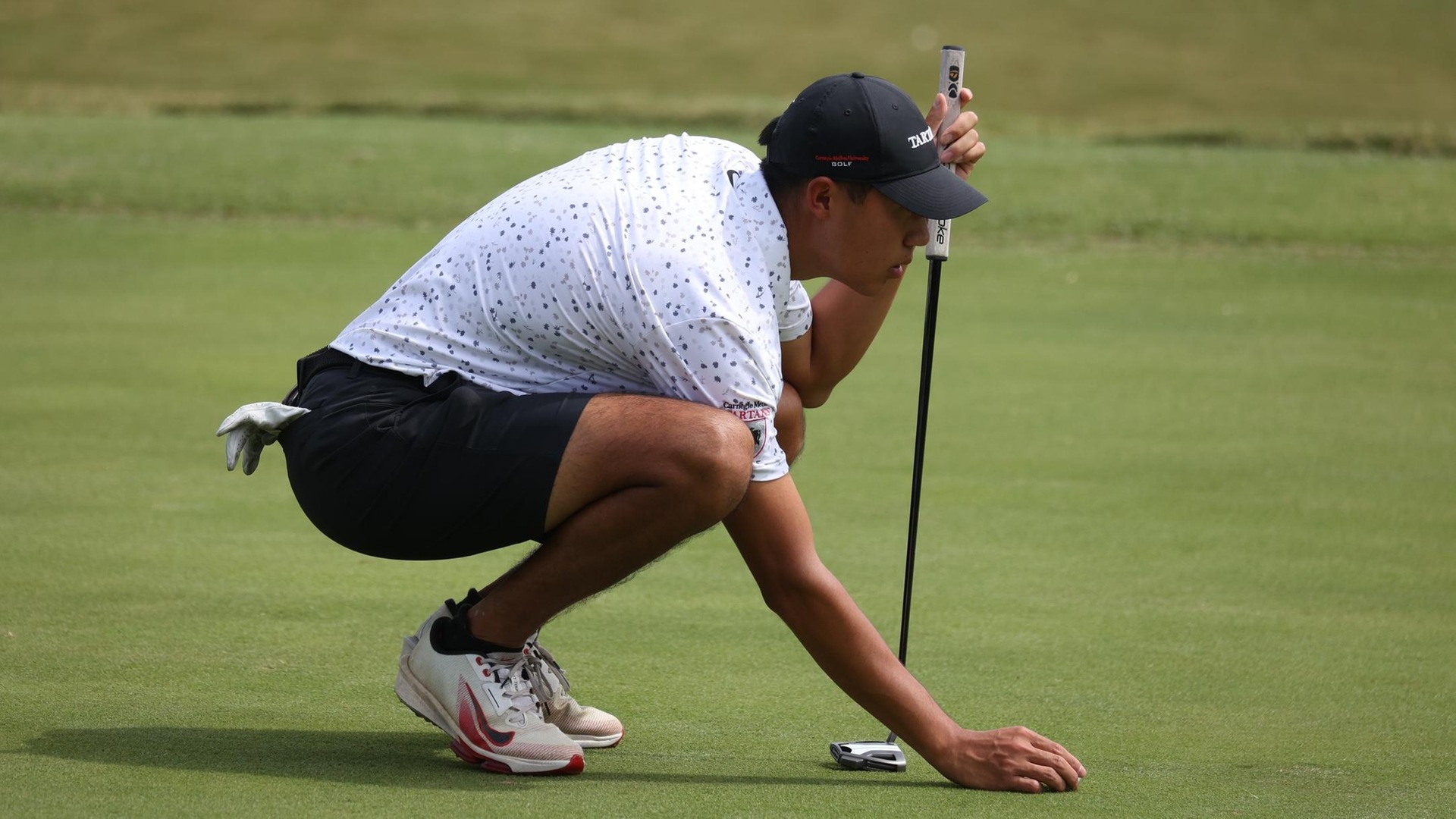 men's golfer kneeling over the ball