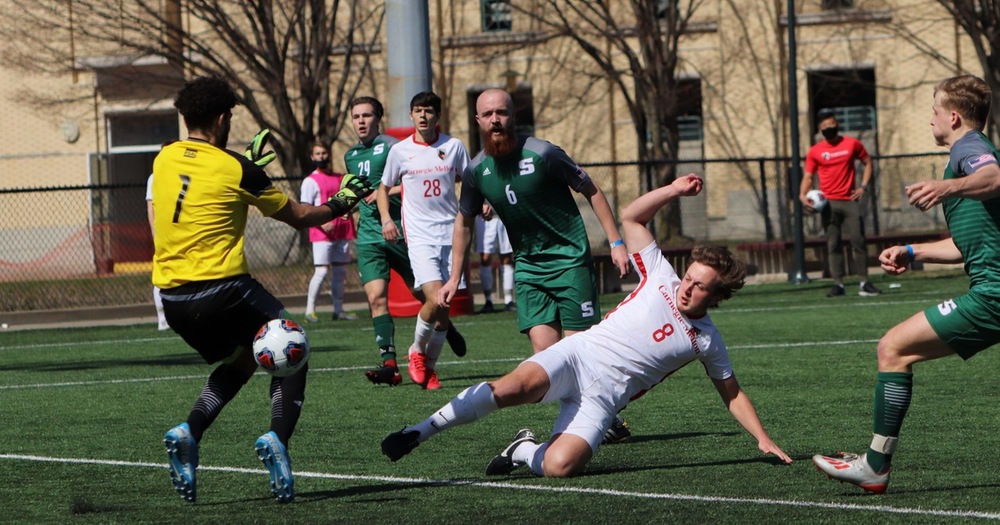 men's soccer player falling to the ground after taking a shot with the ball going passed the keeper