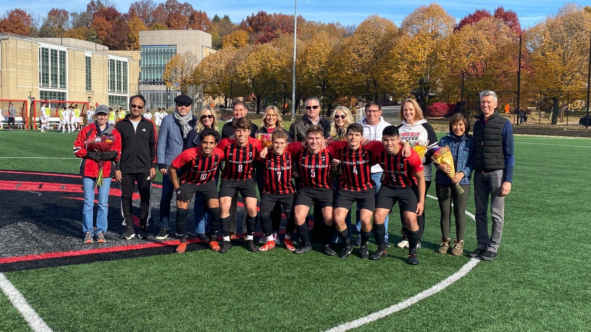 group photo of men's soccer players in front row with family members behind them