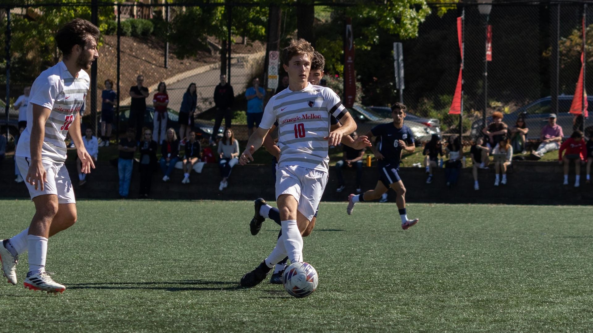 men's soccer player wearing a white uniform has the ball at his right foot