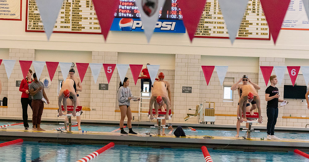 Men's swimmers preparing to jump off the starting block