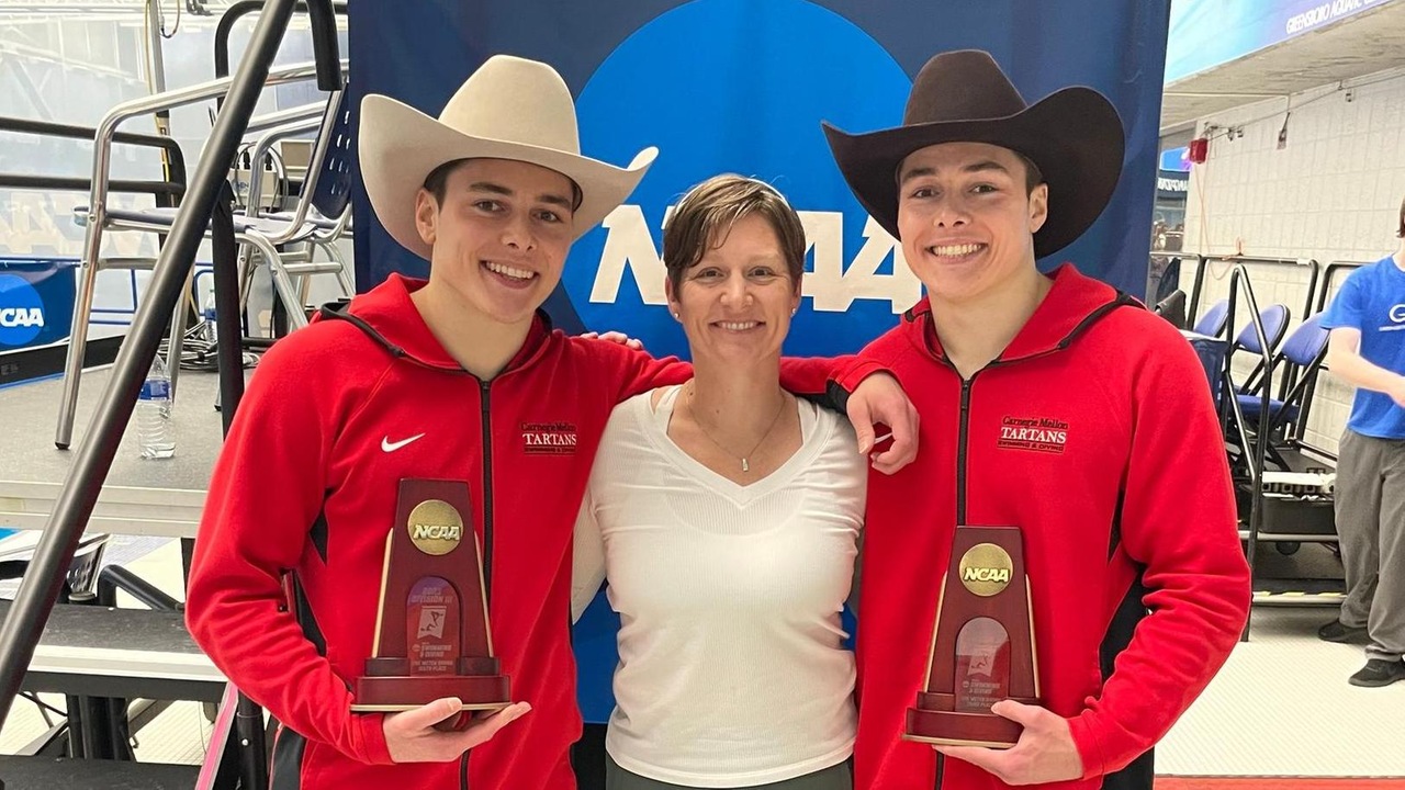 three people standing together with two holding trophies