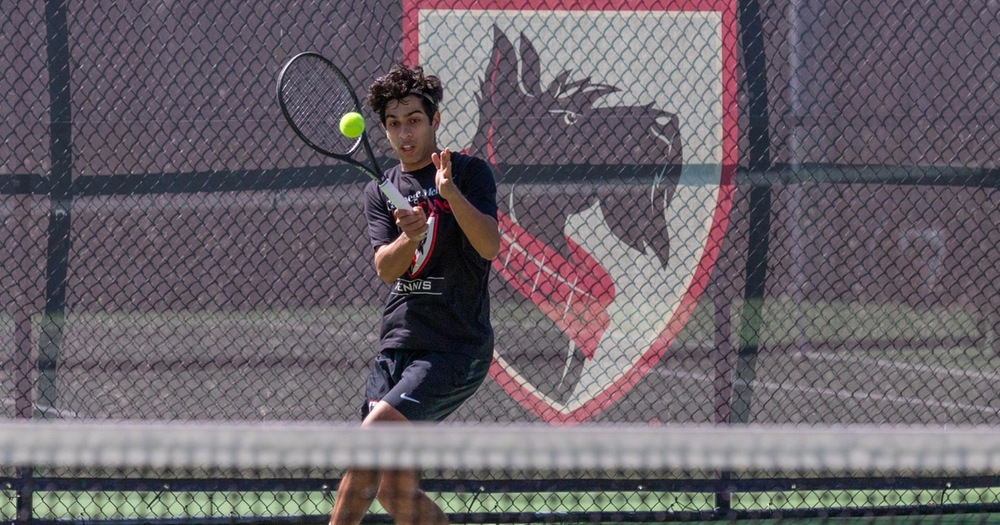 men's tennis player returning a shot with the net in the foreground