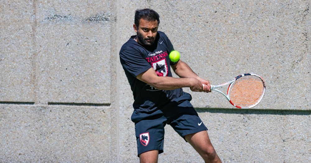 men's tennis player wearing black shirt and black shorts about to hit a return shot