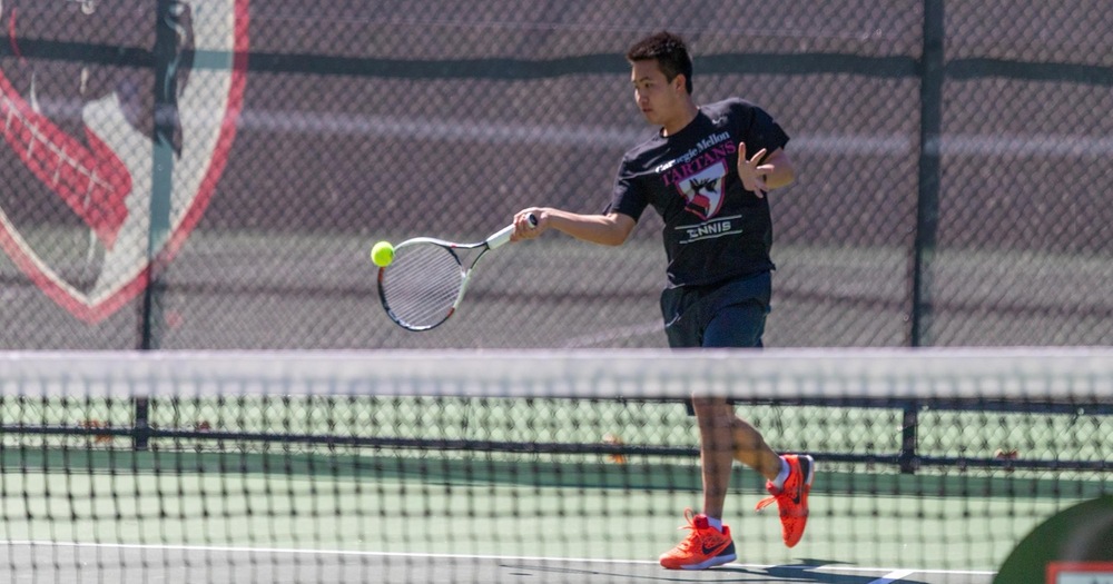 men's tennis player wearing a black shirt and black shorts hitting a forehand shot