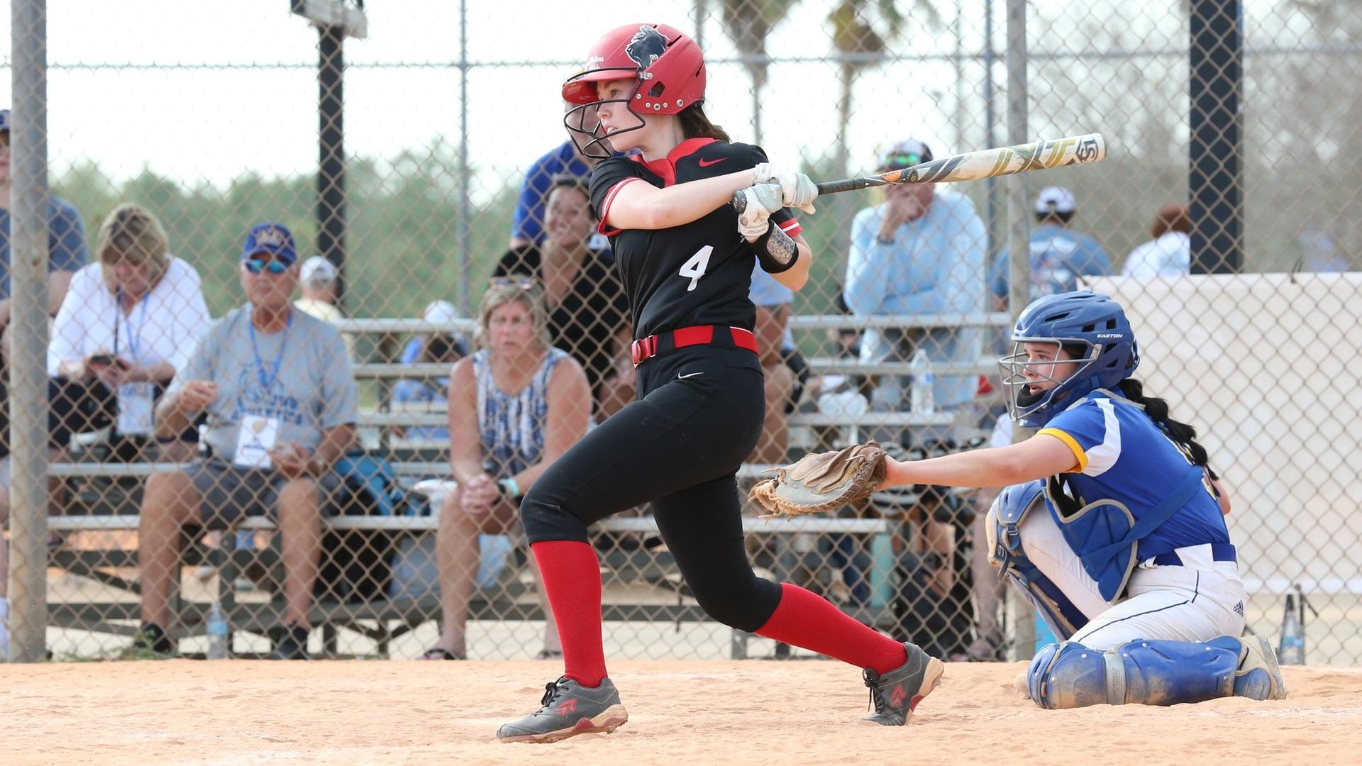 women's softball player swinging through a pitch