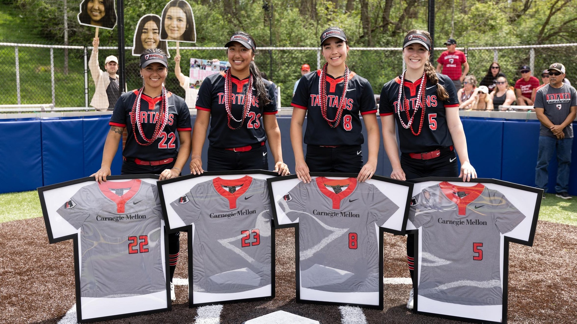 four women's softball players standing at home plate framed jerseys