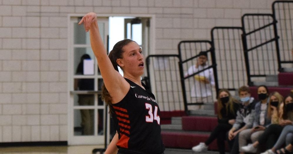 women's basketball player wearing black uniform holding hand up after a shot