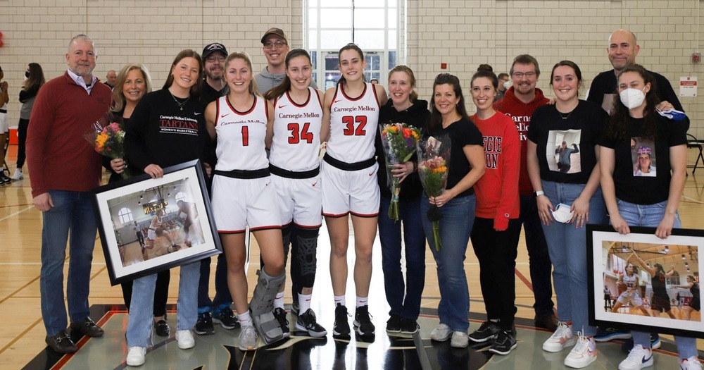 group of people standing together focused on three women's basketball players wearing white uniforms