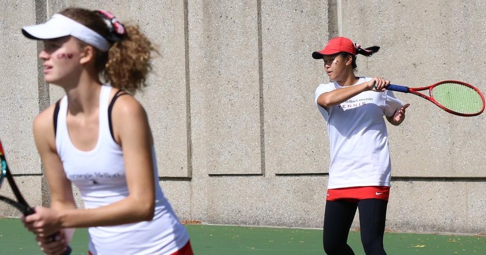 women's tennis doubles team with one close up at the net and the second player returning a shot 