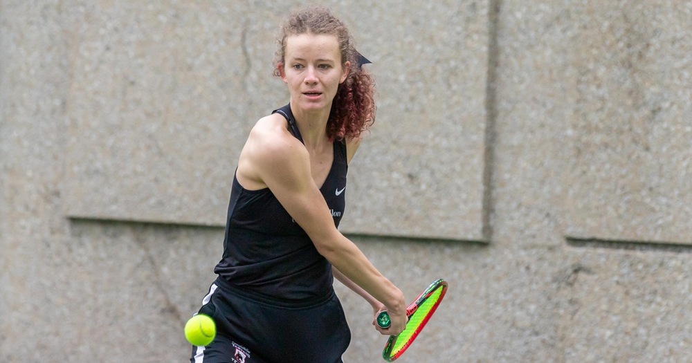women's tennis player wearing all black about to hit the ball