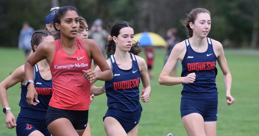 women's cross country runners grouped together near start of race