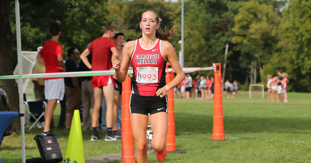 women's cross country runner crossing the finish line