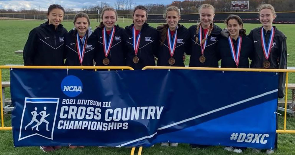 group photo of eight women's cross country runners standing behind a banner wearing medals